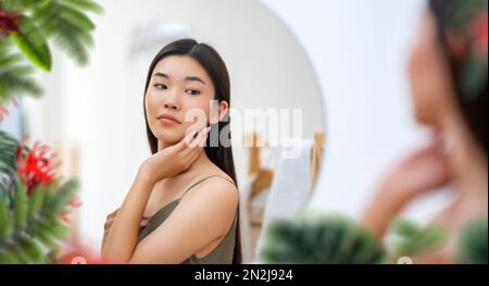 Portrait d'une jeune femme attrayante regardant le miroir. Belle fille appréciant son reflet, concept d'auto-soin. Banque D'Images