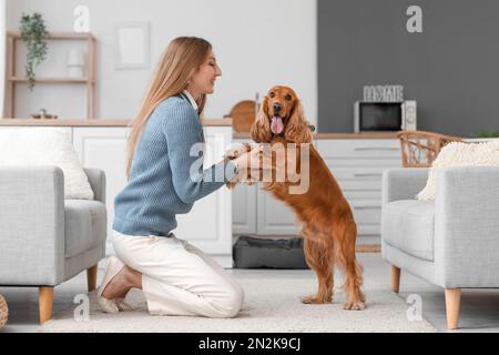 Jeune femme avec un épagneul cocker rouge dans la cuisine Banque D'Images