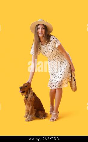 Jeune femme avec un spaniel de cocker rouge sur fond jaune Banque D'Images