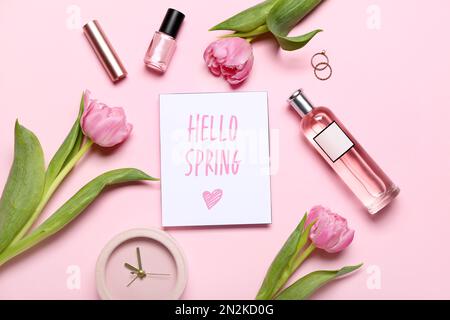 Composition avec carte, bouteille de parfum, fleurs de tulipe et cosmétiques sur fond rose. Bonjour printemps Banque D'Images