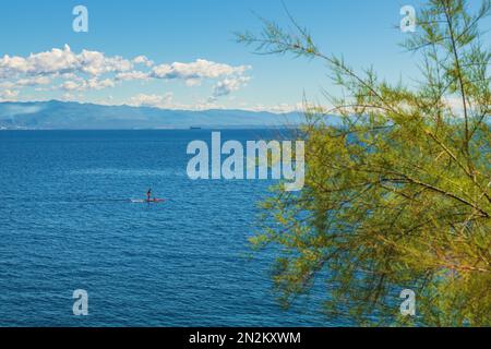 Personne méconnaissable paddle-board debout sur la mer Adriatique du golfe de Kvarner vue de la côte de la ville de Lovran, attention sélective Banque D'Images