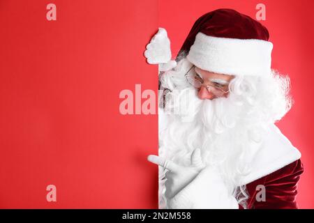 Le Père Noël tient une bannière vide sur fond rouge Banque D'Images