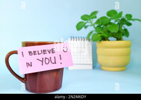 Je crois en vous des mots d'encouragement et de confiance. Mise au point sélective d'une tasse de café avec note de message manuscrite sur papier brillant. Banque D'Images