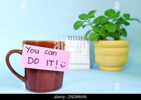 Vous pouvez le faire mots d'encouragement concept. Mise au point sélective d'une tasse de café avec note de message manuscrite sur papier brillant. Banque D'Images