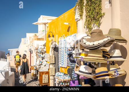 Oia, Grèce - août 2022 : vente de chapeaux en osier dans une boutique de souvenirs située parmi les bâtiments jaunes de la ville d'Oia sur l'île de Santorini Banque D'Images