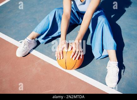 Basket-ball, mains et femme sur le terrain extérieur avec la mode urbaine pour la beauté influenceur. Sport, mannequin et jeune assis avec gen z Banque D'Images