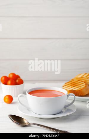 Soupe de tomates fraîches dans un bol blanc sur fond de bois. Vue latérale. copier l'espace Banque D'Images