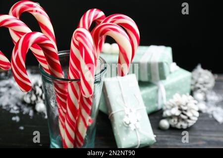 Beaucoup de bonbons de Noël doux Cannes et boîtes-cadeaux sur table en bois noir. Espace pour le texte Banque D'Images