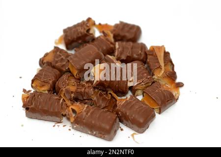 petits morceaux de barres de chocolat bâtonnets remplis de biscuits, caramel et chocolat isolés sur fond blanc, foyer sélectif de confiserie sucrée Banque D'Images