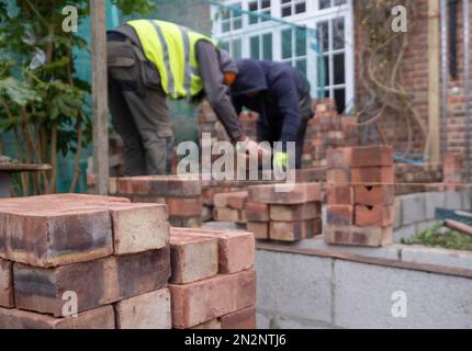 Deux ouvriers de la construction qui poncent des briques dans le cadre de la rénovation d'une maison de banlieue édouardienne dans le nord de Londres, au Royaume-Uni Banque D'Images