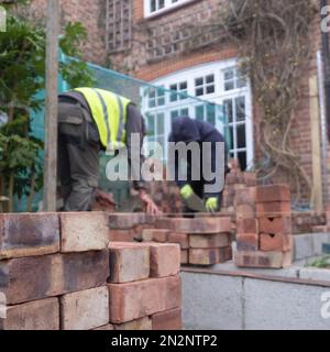 Deux ouvriers de la construction qui poncent des briques dans le cadre de la rénovation d'une maison de banlieue édouardienne dans le nord de Londres, au Royaume-Uni Banque D'Images