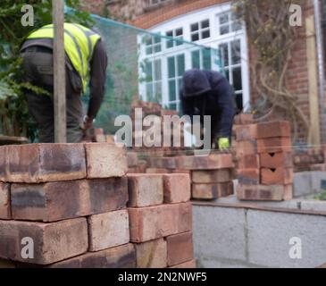 Deux ouvriers de la construction qui poncent des briques dans le cadre de la rénovation d'une maison de banlieue édouardienne dans le nord de Londres, au Royaume-Uni Banque D'Images