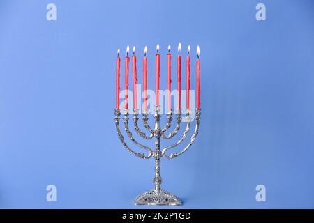 Menorah argentée avec bougies allumées sur fond bleu clair. Célébration Hanukkah Banque D'Images