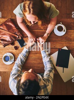 Couple tenant les mains, l'amour et la date au café le jour de Valentines, confiance et soin, table en bois vue sur le dessus..personnes dans le café, le soutien et le respect avec Banque D'Images
