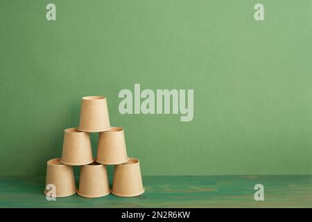 Pile pyramidale de tasse brune sur table en bois. arrière-plan vert. développement de l'entreprise concept de croissance de la réalisation Banque D'Images