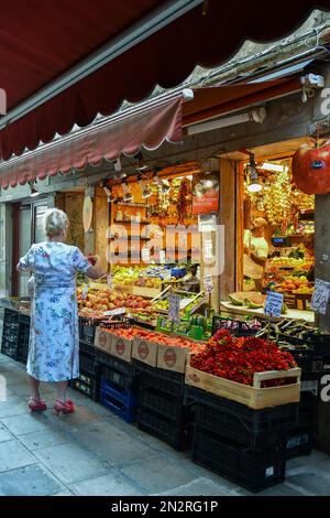 Une élégante dame de premier plan magasine dans une épicerie de Salizada San Canzian dans la sestiere de Cannaregio en été, Venise, Vénétie, Italie Banque D'Images