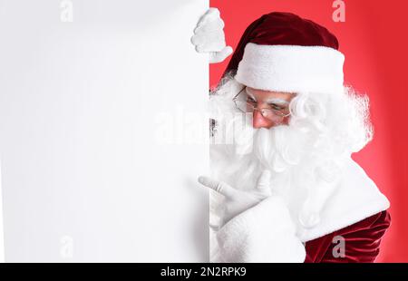 Le Père Noël tient une bannière vide sur fond rouge Banque D'Images