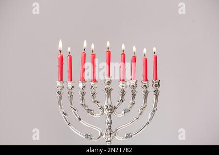 Menorah argentée avec bougies allumées sur fond gris clair. Célébration Hanukkah Banque D'Images