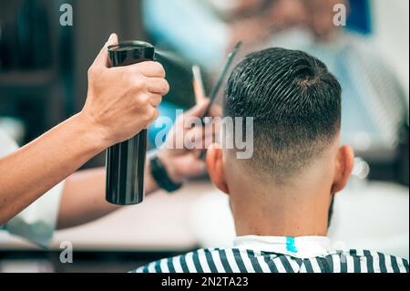 Vue arrière du client masculin ayant coupé la coiffure pendant la récolte barber mouillant les cheveux dans le salon de coiffure moderne Banque D'Images