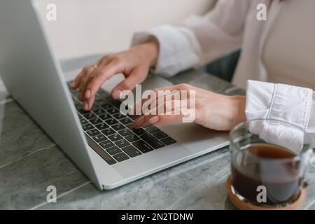 Gros plan d'une femme assise sur un bureau travaillant sur son ordinateur portable Banque D'Images