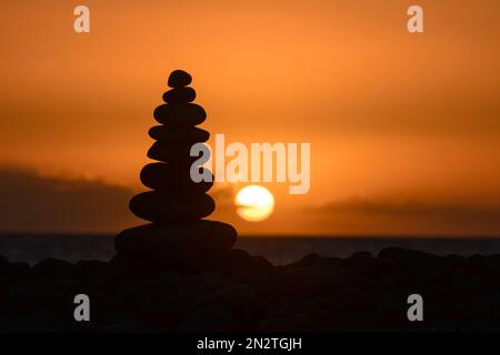 Silhouette d'une pile de galets sur la plage au coucher du soleil, Playa de Arguineguin, Gran Canaria, îles Canaries, Espagne Banque D'Images