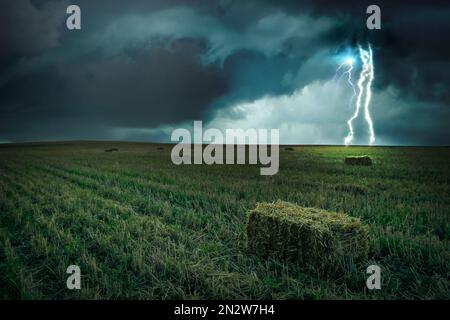 Bel orage sur le champ vert. La foudre frappe depuis un ciel sombre et nuageux Banque D'Images