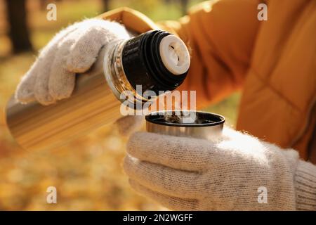 Femme versant de la boisson des thermos dans le bouchon à l'extérieur, gros plan Banque D'Images