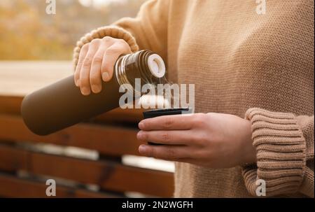 Femme versant de la boisson des thermos dans le bouchon à l'extérieur, gros plan Banque D'Images