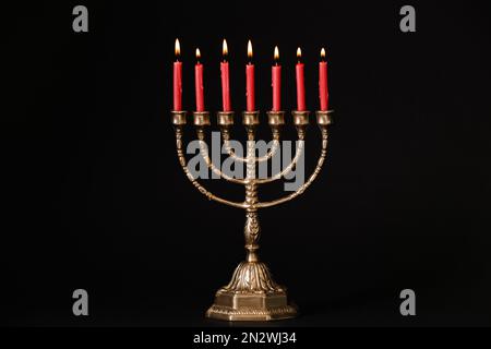 Menorah dorée avec bougies allumées sur fond noir Banque D'Images