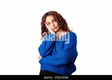 Femme mignonne debout isolée sur fond blanc regardant réticent et peu amusé à la caméra, penchée visage sur la main. Écouter personne ennuyeuse. Écoute Banque D'Images