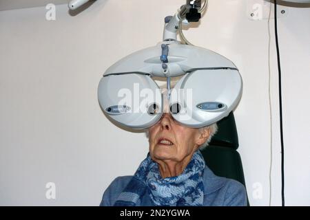 WEoman soumis à un test oculaire en utilisant un équipement moderne Nidek hi-tech pour tester la vue UK Banque D'Images