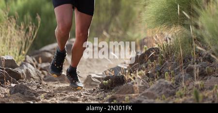 Piste d'athlète en montagne sur terrain rocailleux, détail chaussures de sport Banque D'Images