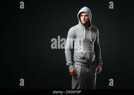 Studio portrait de jeune garçon cool look dans les vêtements de sport debout sur fond gris foncé. Banque D'Images