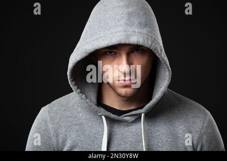 Studio portrait de jeune garçon cool look dans les vêtements de sport debout sur fond gris foncé. Banque D'Images