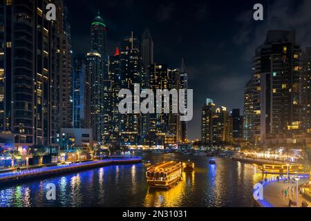 Le paysage urbain de la marina de Dubaï la nuit avec gratte-ciels éclairés et bateaux dans le canal. EAU Banque D'Images