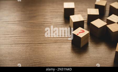 Mise au point sélective d'un cube en bois écrit avec un symbole de question sur fond en bois. Banque D'Images