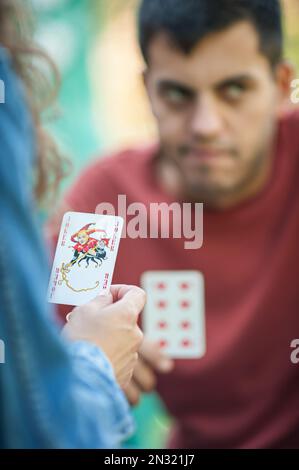 Jouer aux cartes dans le jardin de printemps. Une femme joue des cartes et tient un joker dans sa main. Banque D'Images