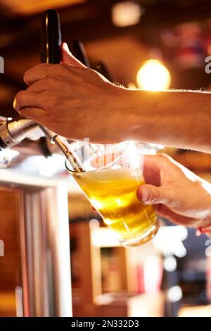 Une photo verticale d'un barman distribuant de la bière dans un verre dans un pub Banque D'Images