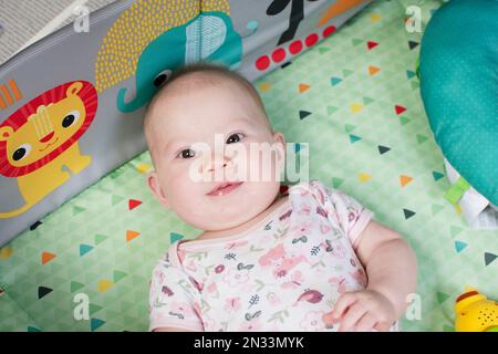 Adorable petite fille caucasienne sur le tapis de jeu. Première année de bébé Banque D'Images