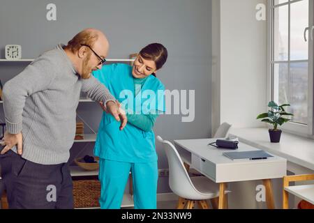 Homme âgé avec des lunettes, marchant tenant le petit de son dos avec l'infirmière soignante. Banque D'Images