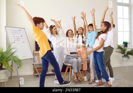 Les élèves des écoles primaires motivés et leur enseignant se soutiennent mutuellement pendant la leçon créative. Banque D'Images