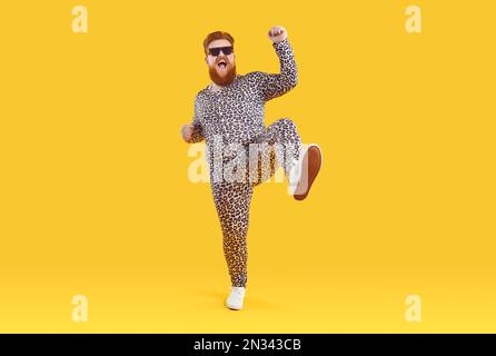 Drôle heureux de taille plus positif homme en costume de pyjama avec imprimé léopard dansant et se moquer autour. Banque D'Images