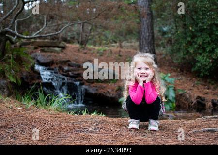 Jeune fille souriante dans un parc. Bébé blond caucasien en randonnée Banque D'Images