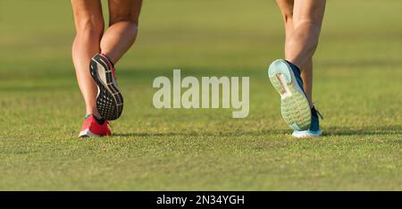 Couple athlètes coureurs pieds courir sur l'herbe. Entraînement de jogging de fitness de la lumière du soleil pour femme. Sport athlète active mode de vie concept. Paire de jambes athlétiques Banque D'Images