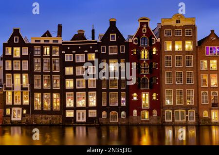 Amsterdam, pays-Bas - 18 janvier 2023 : paysage urbain de maisons hollandaises traditionnelles au coucher du soleil sur le canal de Damrak à Amsterdam Banque D'Images