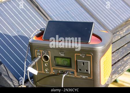 Téléphone mobile chargé par un bloc de batterie de générateur solaire avec des panneaux solaires au soleil Banque D'Images