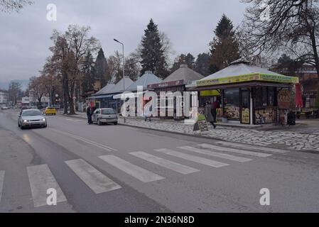 Des personnes qui s'arrêtent dans un layette à côté d'une rangée de magasins et de restaurants à emporter à Velingrad, en Bulgarie Banque D'Images