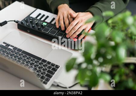 Vue de dessus du producteur ou de l'arrangeur de musique à l'aide d'un ordinateur portable, d'un clavier midi et d'autres équipements audio pour créer de la musique dans un studio à domicile. Battre et Banque D'Images