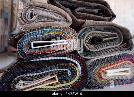 Échantillons de tissus d'ameublement roulés avec un bureau en tissu flou à l'arrière-plan Banque D'Images