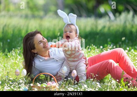 Bonne famille le jour de Pâques, expressif souriant et amusant. La mère joue avec une fille drôle portant des oreilles de lapin avec la carotte. copier l'espace. Bonne childhoo Banque D'Images